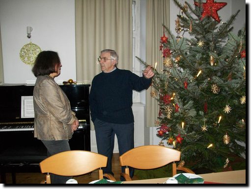 Ehrenvorsitzender Georg Dietrich unterhält sich vor dem Weihnachtsbaum mit der Ehefrau von Ausschussmitglied Rolf Alt aus Geiselberg